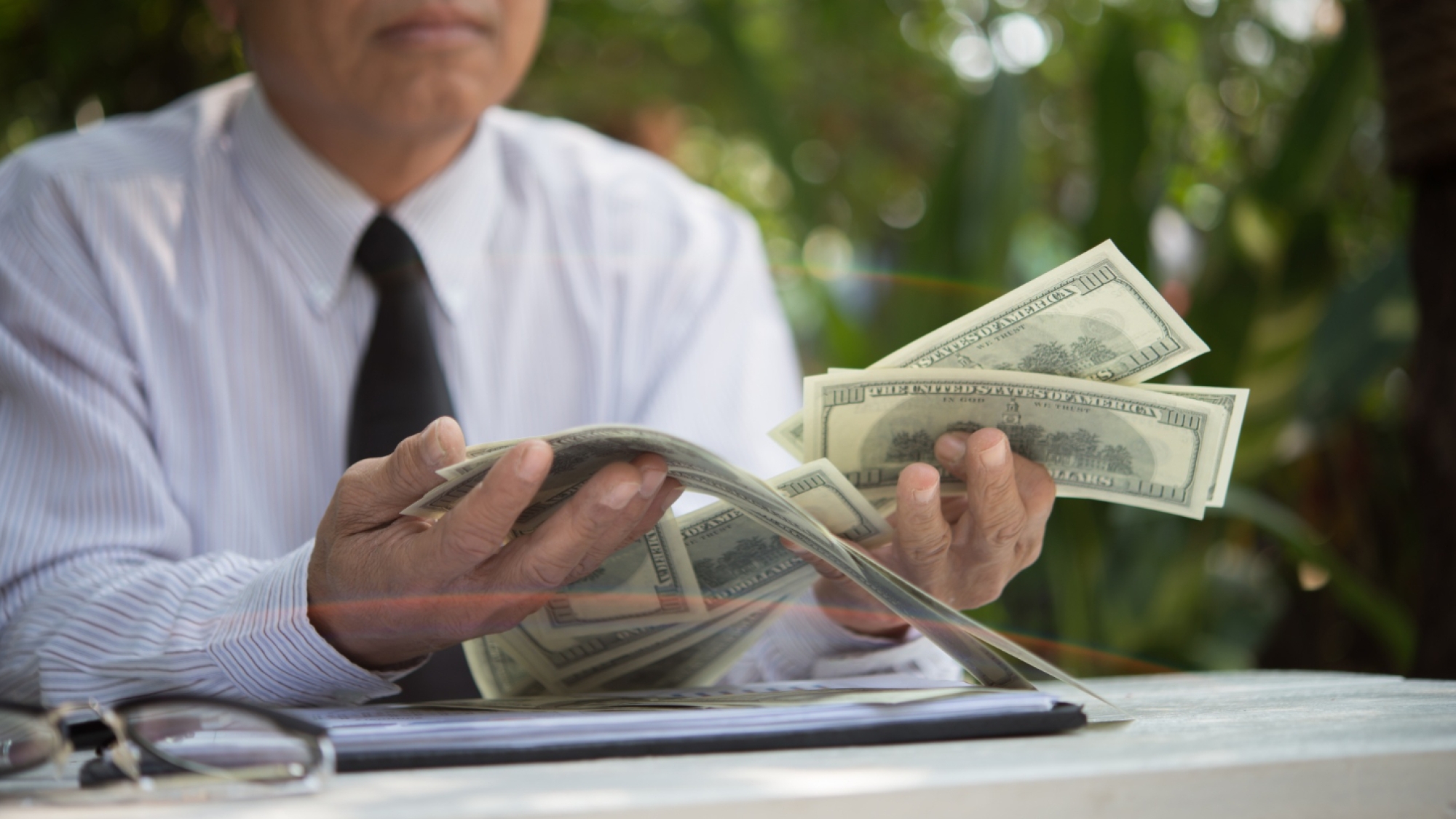 Person flipping through cash while reviewing financial papers