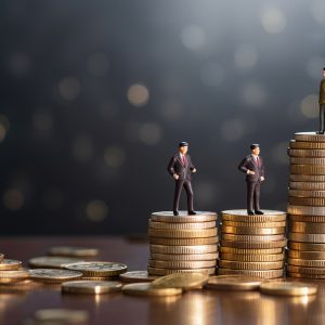 Miniature business figures standing on stacked coins