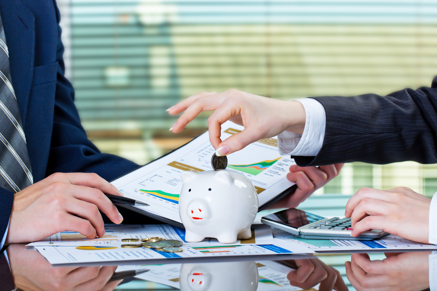 Hands placing a coin into a piggy bank with documents